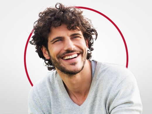 Nasmejan mlad moški v sivem puloverju, zadovoljen po zdravljenju s Canestenom za glivično okužbo pri moških